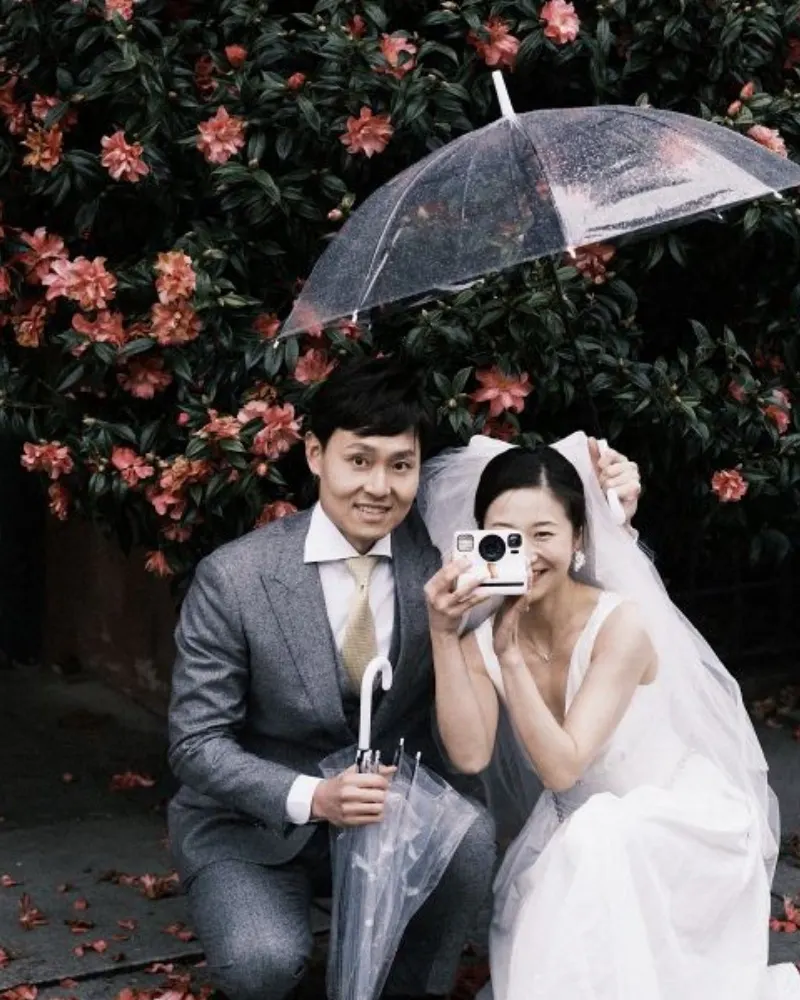 A newlywed couple photographed beneath a clear umbrella